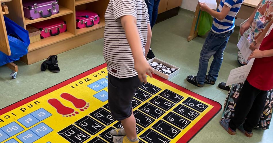 Kinder springen Wörter am Buchstabenteppich